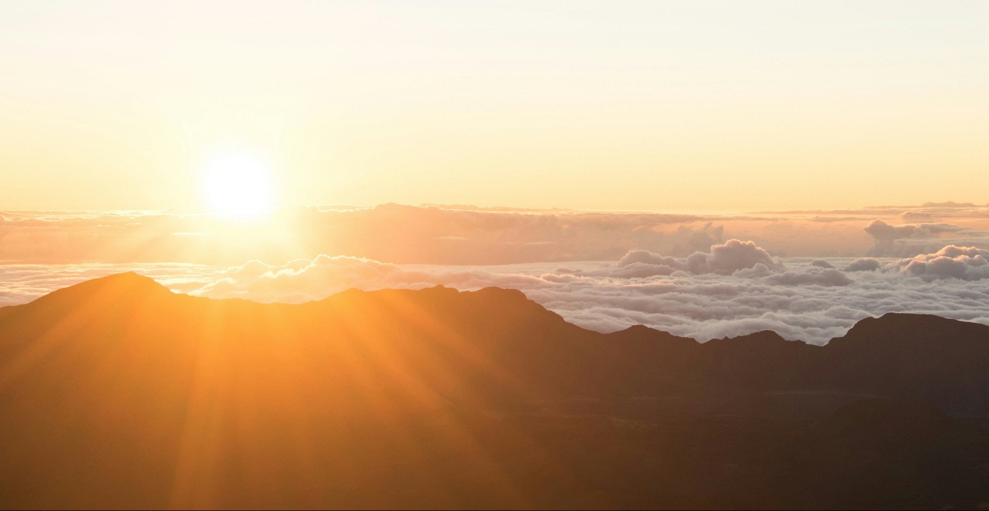 Sunrise over a mountain range with clouds below
